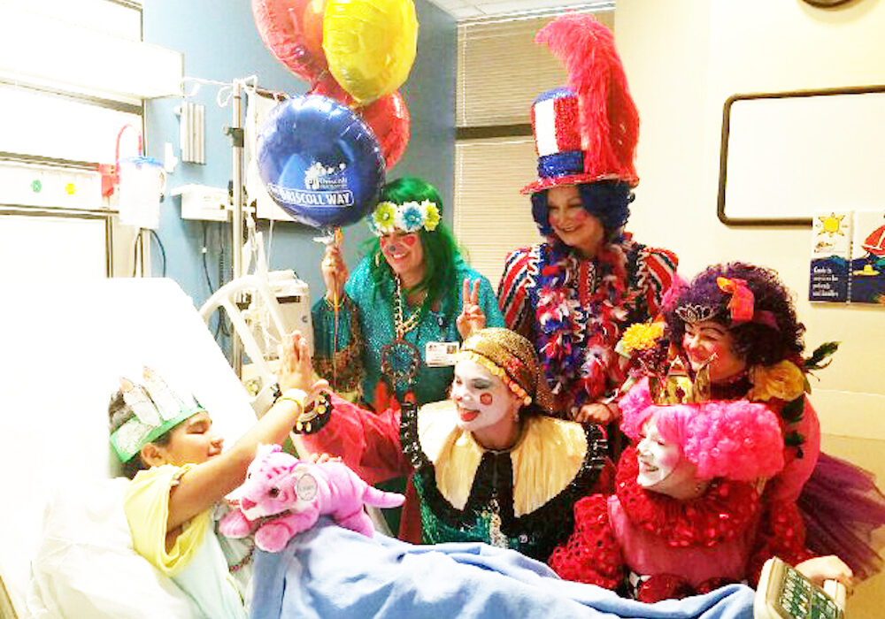 ‘Penelope the Pirate’ (Beth Owens) gives a high-five to 11-year-old patient Uriah Davila at Driscoll Children’s Hospital in Corpus Christi recently. Also clowning around were (from rear left to front right), ‘Hippie Bee Bop’ (Mrsai Bass), ‘Ya Ya Doodle Dandy’ (Bridget McKeever), ‘Princess Tina the Ballerina’ (Laurie Plant ) and ‘Quirky Queen of Hearts’ (Jill Jacobs). Photo by Jane Kathleen Gregorio