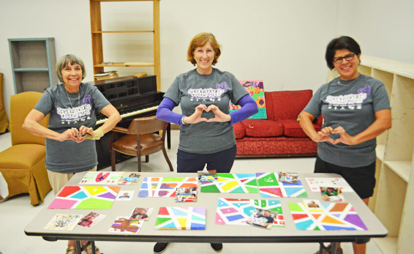Showcasing some of the artwork from Special Hearts in the Arts arecommittee member Susan Long (left), founder Sherri Davis and volunteer Melinda Escamilla. Photo by Jane Kathleen Gregorio