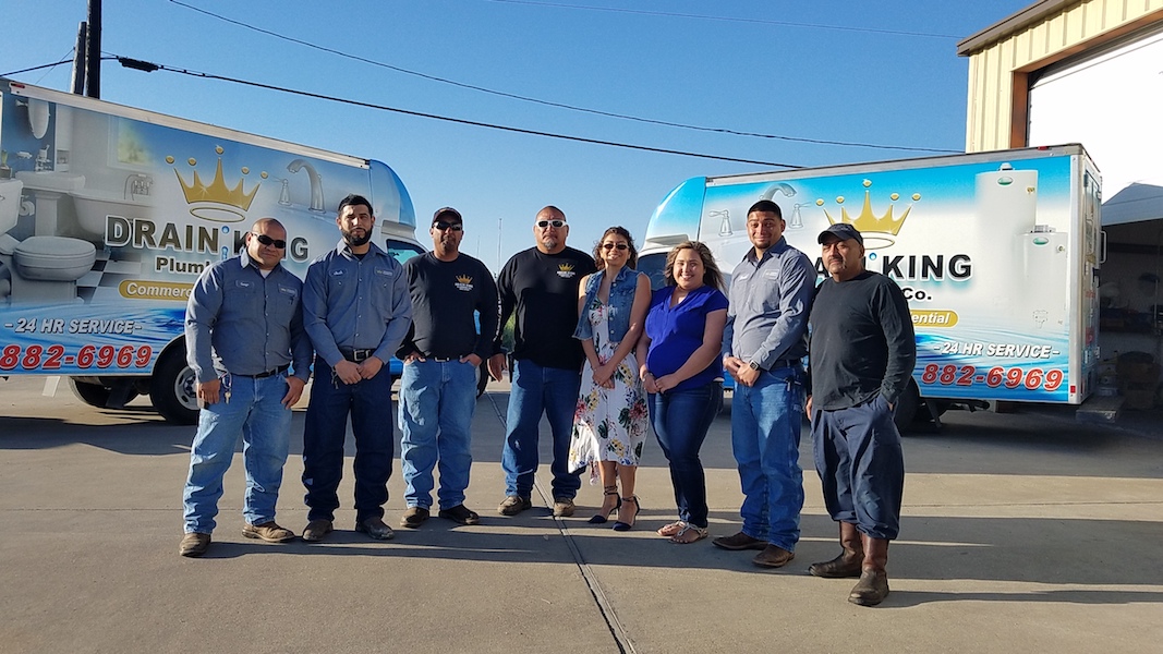 The family of service professionals at Drain King Plumbing, together with company owner Juan Sanches and his wife Rosa Sanches (center), who manages the office. Since acquiring their updated building at 1405 Neptune, they have continued to grow. Photo by Jane Kathleen Gregorio