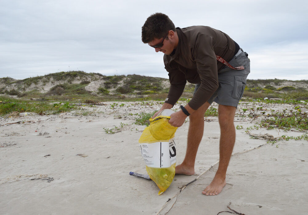 Coullin Croulet, former research assistant at the University of Texas Marine Science Institute, collects marine debris on a Texas beach as part of a two-year-long data collection project conducted by the institute. Courtesy photo by Sally Palmer