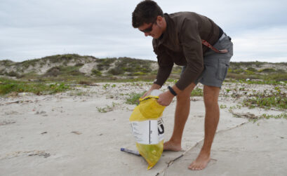 Coullin Croulet, former research assistant at the University of Texas Marine Science Institute, collects marine debris on a Texas beach as part of a two-year-long data collection project conducted by the institute. Courtesy photo by Sally Palmer