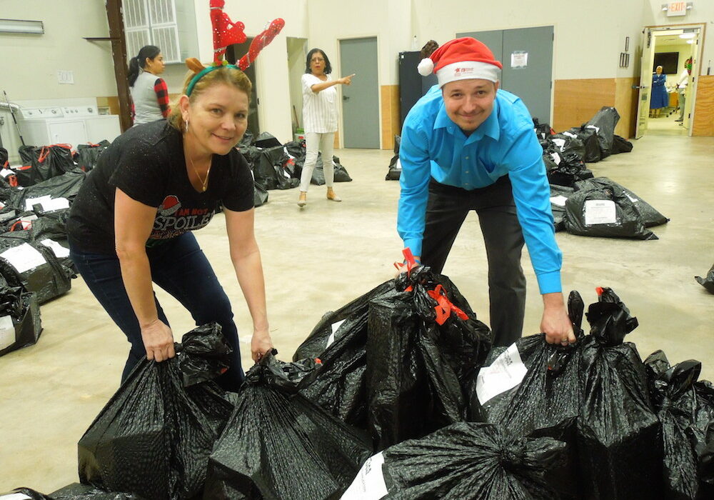 Ninfa Jacobs (left) and Kristofer Morgan move bags of toys sorted for distribution to families during Christmas at Catholic Charities of Corpus Christi Inc. Photo by Dayna Worchel