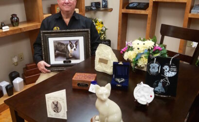 John Gibson with some of the urns available at Corpus Christi Pet Memorial Center. The dog in the photo is “Bobo,” Gibson’s long-time beloved companion. Photo by Jane Kathleen Gregorio