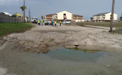 City officials and crews converse over a problem at the Neal Street drainage infall on North Beach on Feb. 9, 2021. In the foreground, poor drainage has caused 'ponding,' where water backs up and creates large pools of water. Photo by Carrie Robertson Meyer/Third Coast Photo