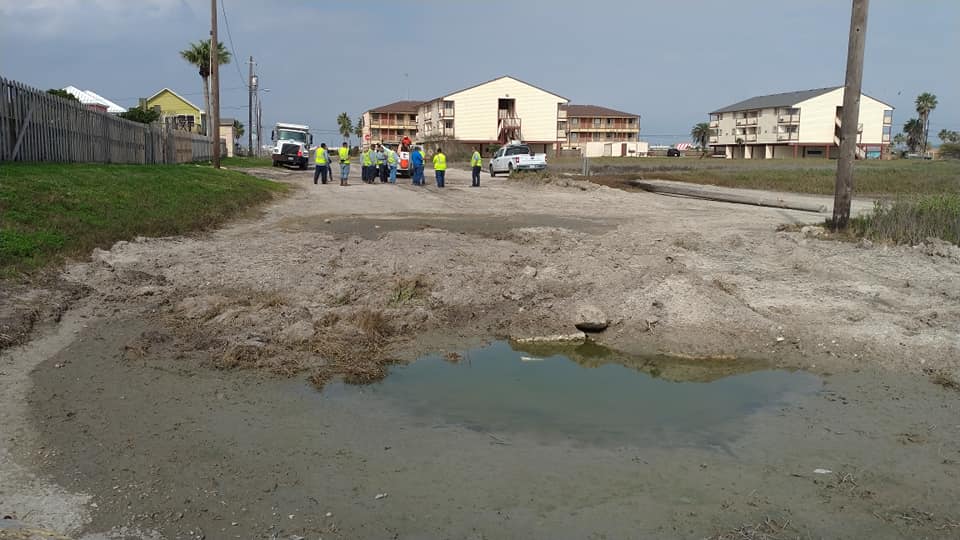 City officials and crews converse over a problem at the Neal Street drainage infall on North Beach on Feb. 9, 2021. In the foreground, poor drainage has caused 'ponding,' where water backs up and creates large pools of water. Photo by Carrie Robertson Meyer/Third Coast Photo