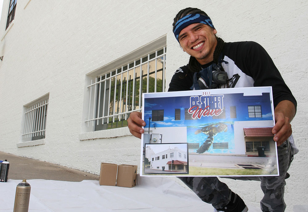 Muralist Jeremy Flores displays the artwork he created of a sea turtle making its way across the sand to the Gulf of Mexico. The illustration will be painted on the wall behind him during CC Street WAVE on July 14-16 in downtown Corpus Christi. Photo by Carrie Robertson Meyer/Third Coast Photo