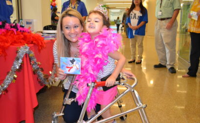 Three-year-old Kendyl proudly shows off her winning artwork of a melting snowman at last year’s celebration of the Driscoll Children’s Hospital Christmas card project. Courtesy photo