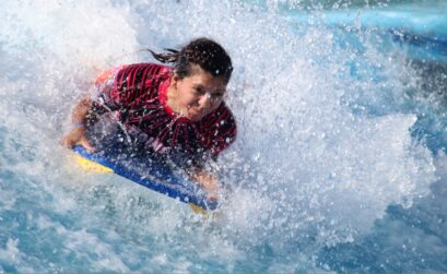 A young surfer rides 50,000 gallons of rushing water at Schlitterbahn Corpus Christi’s inland surfing attraction Boogie-bahn to celebrate National Women Learn to Surf Week. The event was held June 12. Photo by Carrie Robertson Meyer/Third Coast Photo