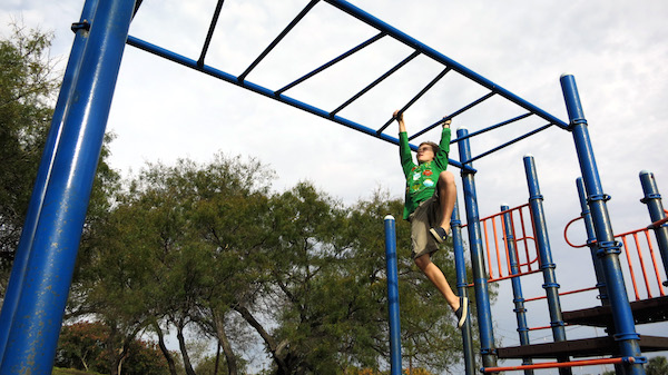 Kai Meyer enjoys the monkey bars at Cabra Park in Corpus Christi. The park is one of 14 that the city has sold. Photo by Third Coast Photo