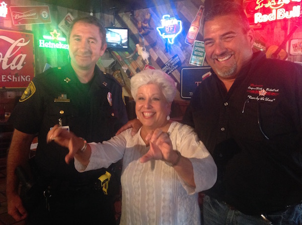 There was no motorcycle for photo ops, so Corpus Christi Mayor Nelda Martinez modeled best riding practices, along with (left) CCPD Capt. Billy Breedlove and BikeFest organizer G.J. Reyna at Brewster Street Ice House August 13. Photo Suzanne Freeman