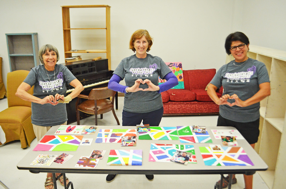 Showcasing some of the artwork from Special Hearts in the Arts arecommittee member Susan Long (left), founder Sherri Davis and volunteer Melinda Escamilla. Photo by Jane Kathleen Gregorio