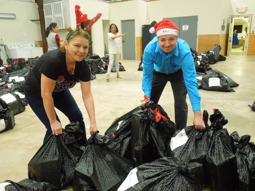 Ninfa Jacobs (left) and Kristofer Morgan move bags of toys sorted for distribution to families during Christmas at Catholic Charities of Corpus Christi Inc. Photo by Dayna Worchel